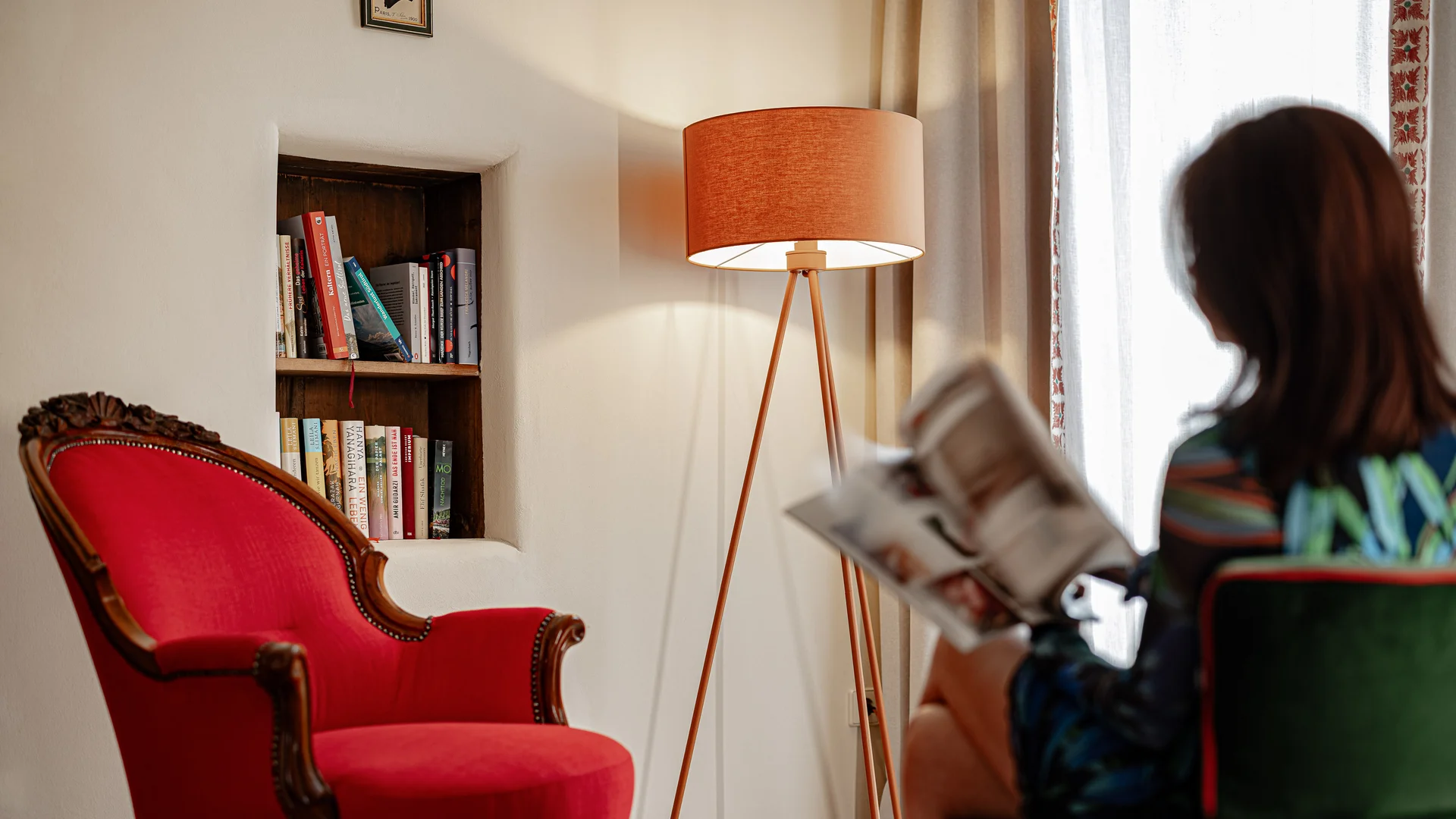 Castel Sallegg Suites: Adults-only Boutiquehotel im Weingut Frau liest in gemütlichem Raum mit rotem Sessel und Stehlampe