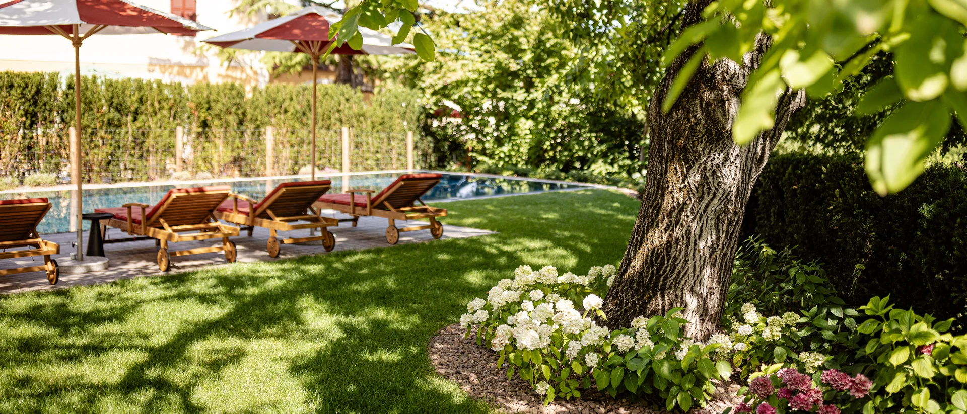 Castel Sallegg Suites: Adults-only Boutiquehotel im Weingut Garten mit Liegestühlen und Sonnenschirmen neben einem Pool